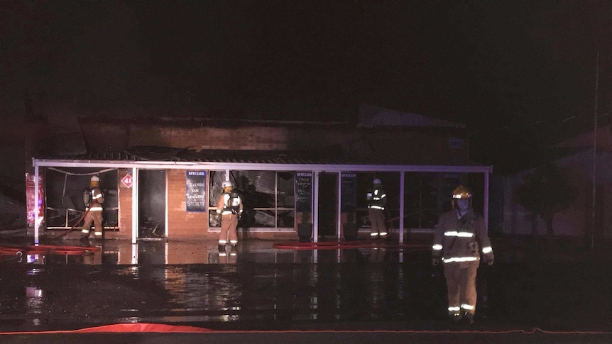 Firefighters outside a gutted building.