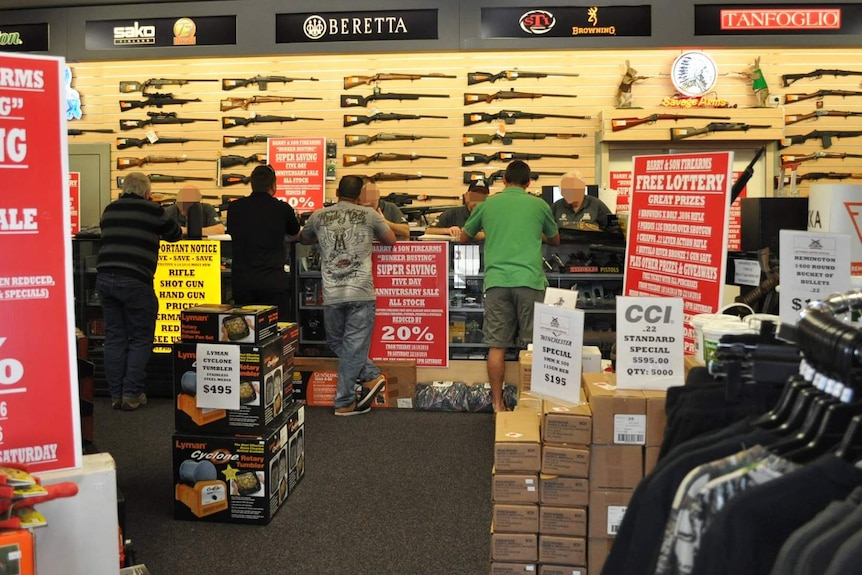 Customers facing staff over the counter at Barry and Son Firearm store.