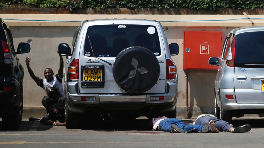 A man comes out from hiding under a car next to bodies in the Westgate mall carpark.