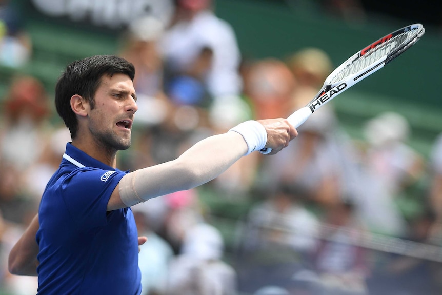 Novak Djokovic plays a forehand while wearing an arm bandage at the Kooyong Classic.