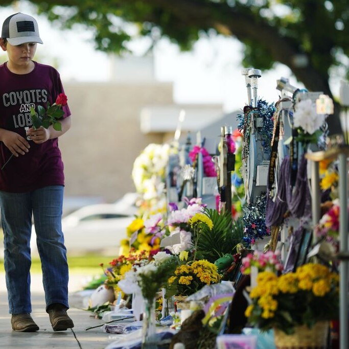Children carry flowers to a mass shooting memorial in Uvalde, Texas