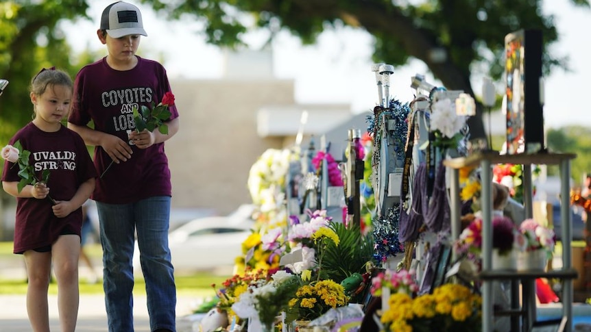 Children carry flowers to a mass shooting memorial in Uvalde, Texas