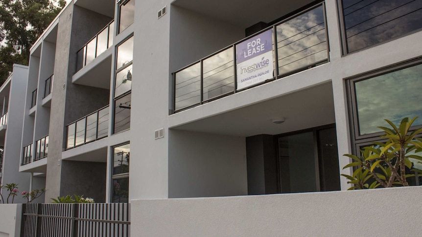 A newly-built apartment building with for lease sign.