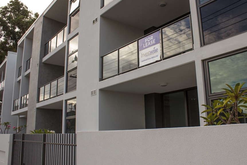 A newly-built apartment building with for lease sign.