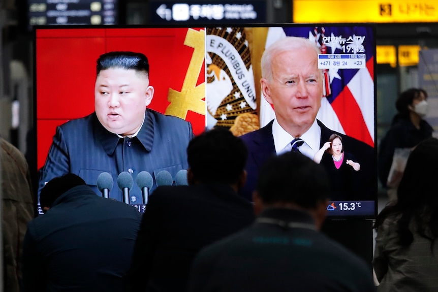Les banlieusards regardent une télévision montrant une image de fichier du dirigeant nord-coréen Kim Jong-un et du président américain Joe Biden.