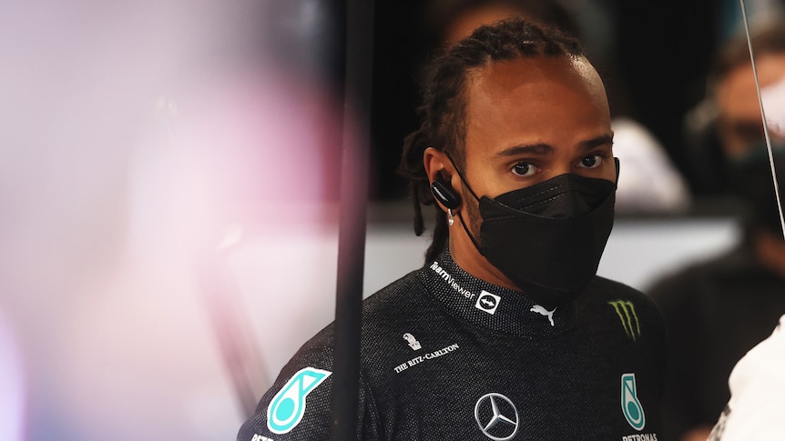 Lewis Hamilton looks at the camera, wearing a facemask