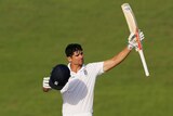 England's Alastair Cook holds a cricket bat in the air in celebration.
