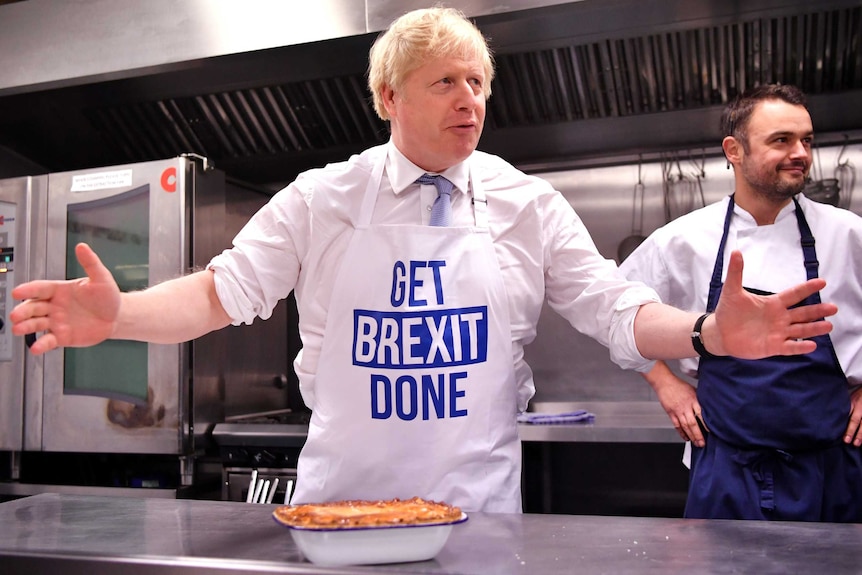 A man in front of a pie gestures with his hands.