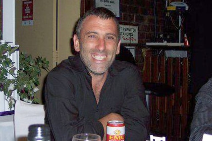 Troy Milbourne sitting at a restaurant table smiling.