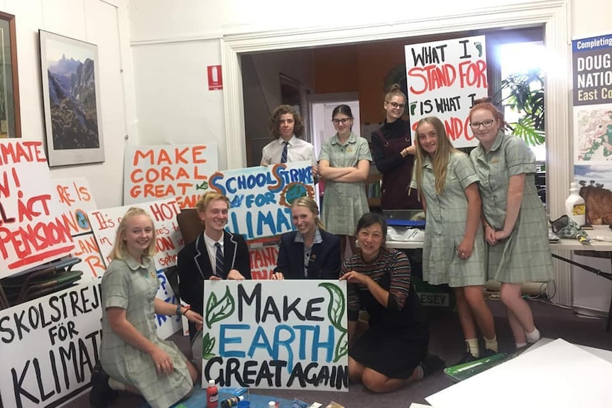 Students surrounded by climate change placards, including one that says: "Make coral great again".