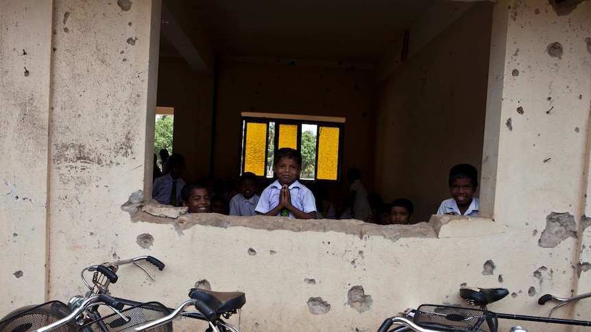 Young students stand inside a school marked by bullet holes pictured in 2011