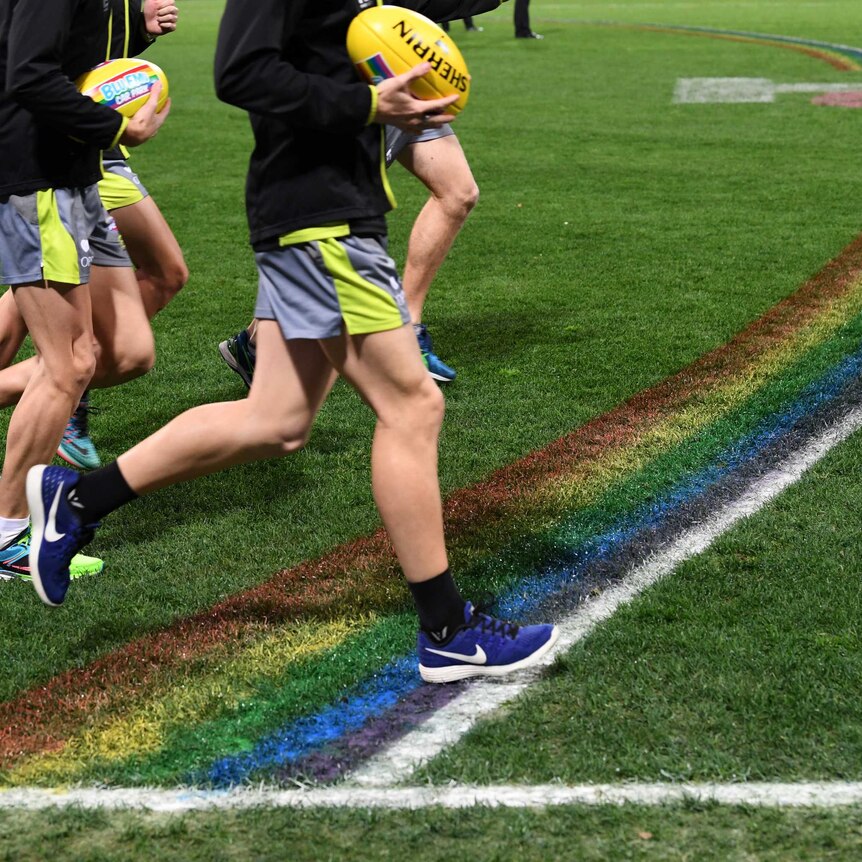AFL umpires run past the rainbow 50-metre arc