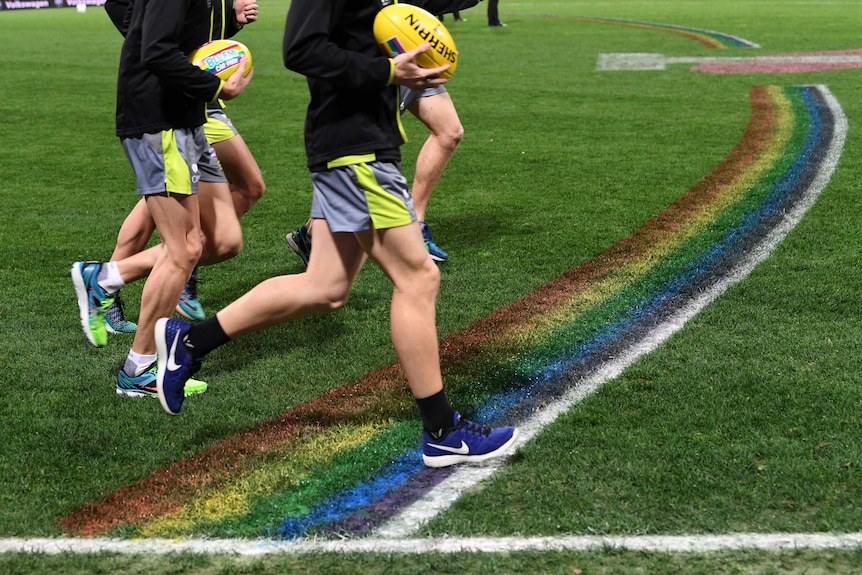 AFL umpires run past the rainbow 50-metre arc