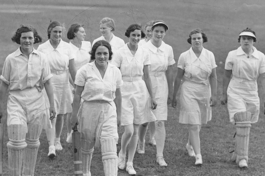 A group of 13 school girls dressed in white cricket attire