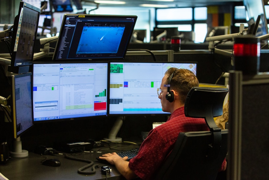 A man sat behind a nest of computer screens