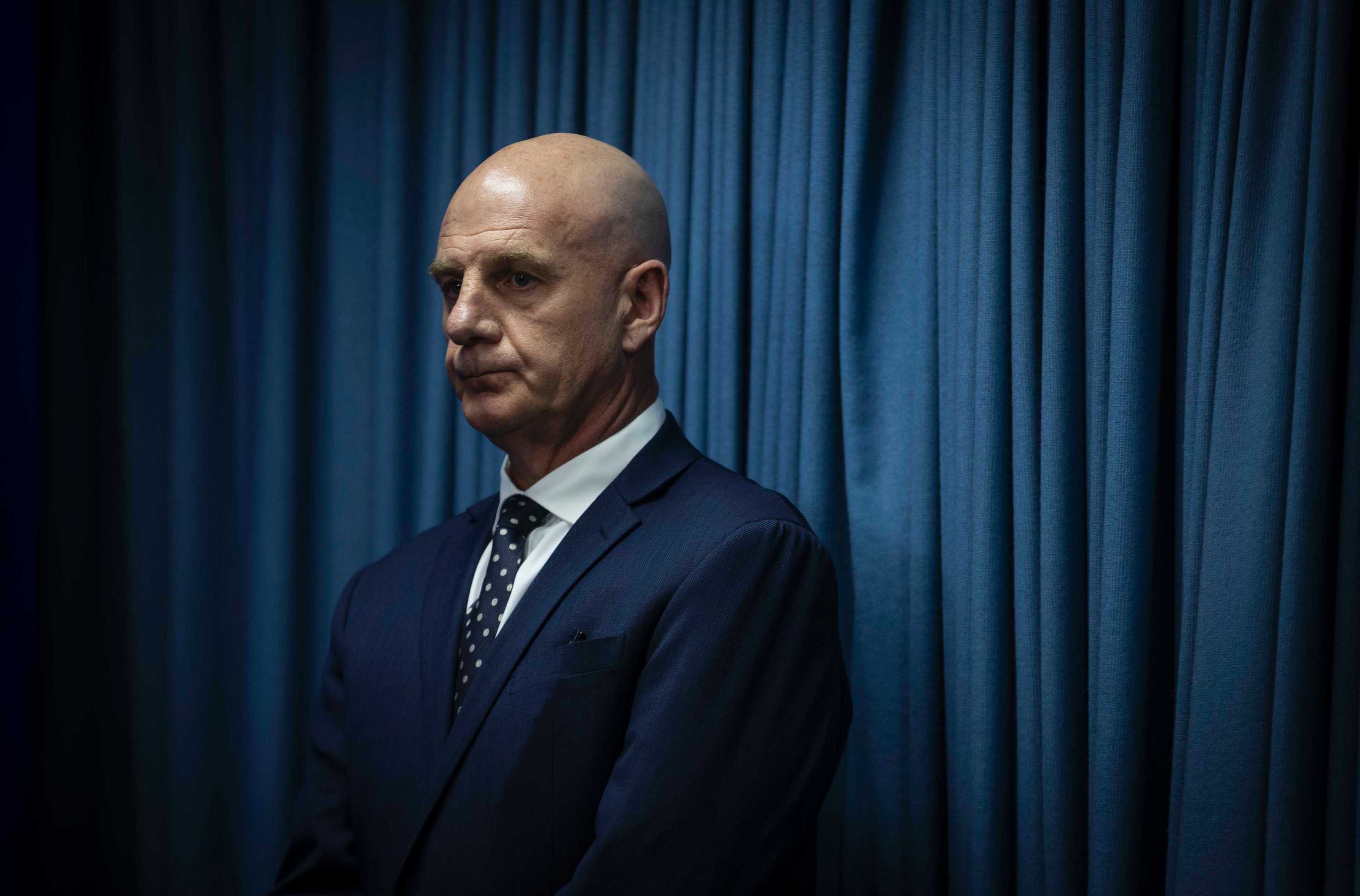 Peter Gutwein standing in front of blue curtain.