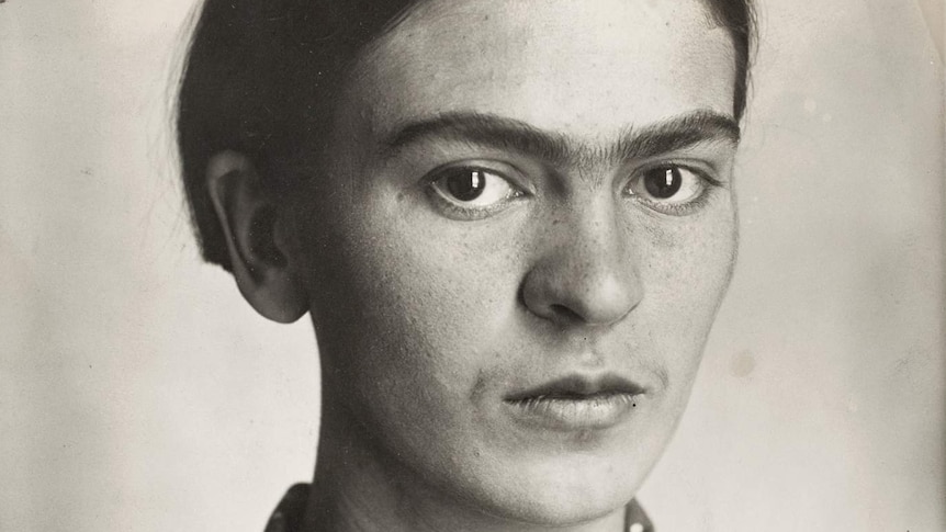 Frida Kahlo as a young girl stares out of black and white photograph at the viewer.