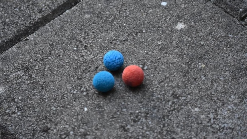 Two blue balls and one red ball on a brick