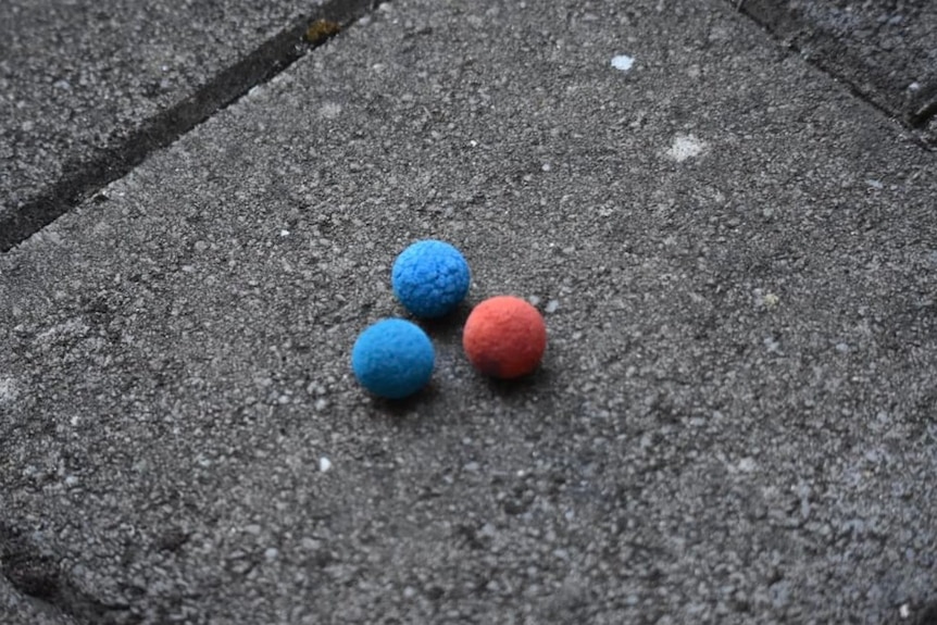 Two blue balls and one red ball on a brick