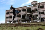 A Syrian man performs a parkour move in front of a damaged building in the Syrian city of Inkhil.
