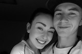 A black and white image of two teenagers, Haylee and Nathan, hugging and smiling at the camera. 