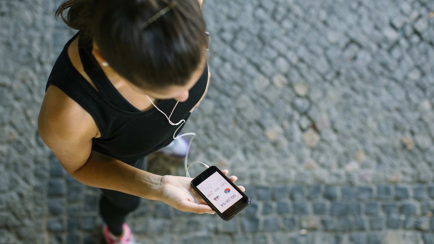 A woman in sports gear looks at her mobile phone