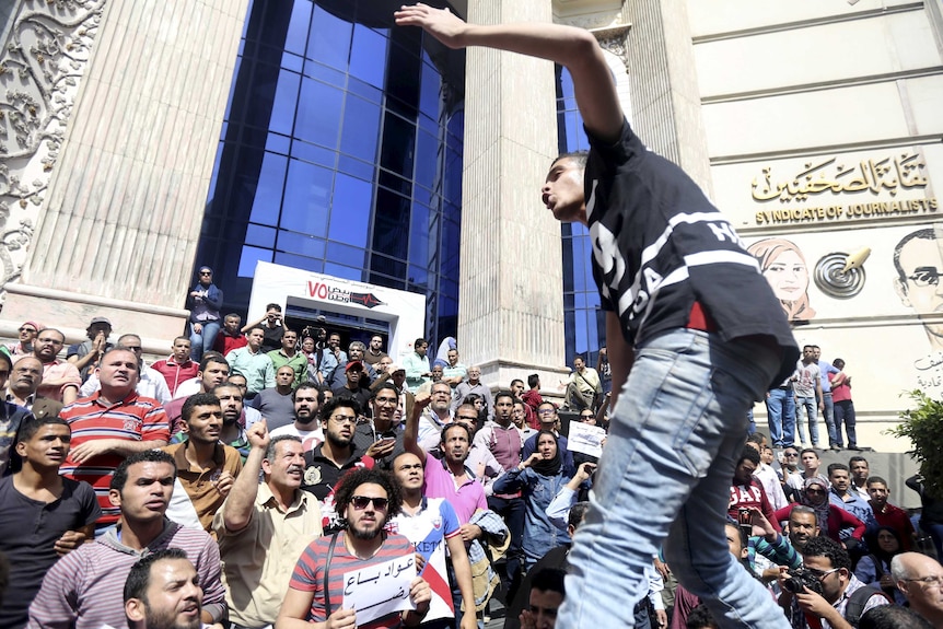 Dozens of protesters holding signs and shouting slogans in Cairo.