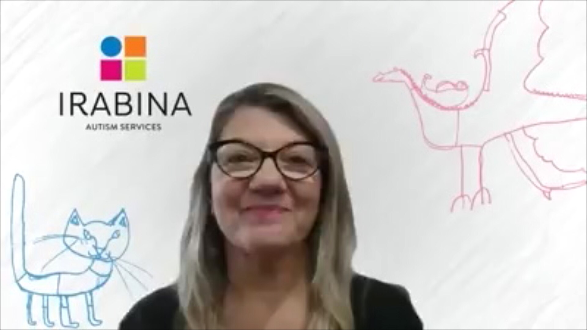 A woman smiles, in a still from a video call, with a Irabina company background behind her with children's drawings on it.