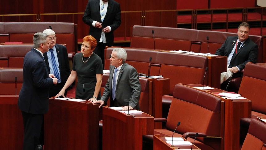 One Nation senators Pauline Hanson and Malcolm Roberts speak to Mathias Cormann, Rod Culleton sits alone.