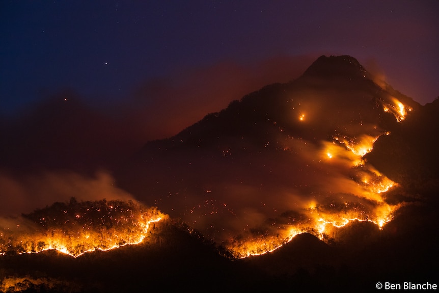 A mountain on fire at night.
