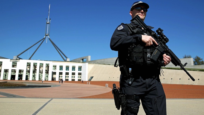 An AFP officer patrols the front of Parliament House