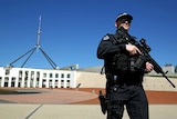 An AFP officer patrols the front of Parliament House