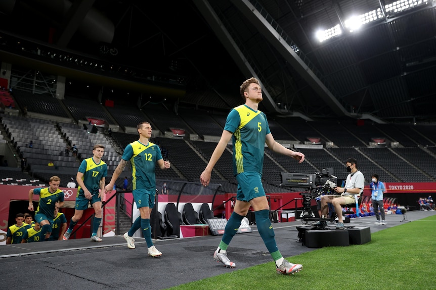 Harry Souttar leads Australia up some stairs into an empty stadium