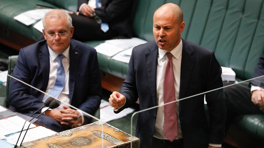 Josh Frydenberg speaks in parliament behind a clear glass screen. Scott Morrison is seated to his right, listening.