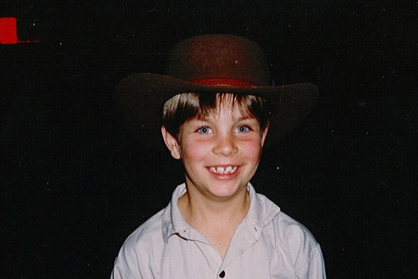 Tim Smith, aged 8, smiles while wearing a large hat.