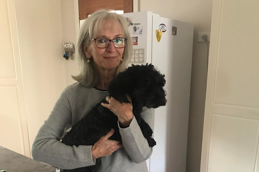 woman with glasses holds black fluffy dog