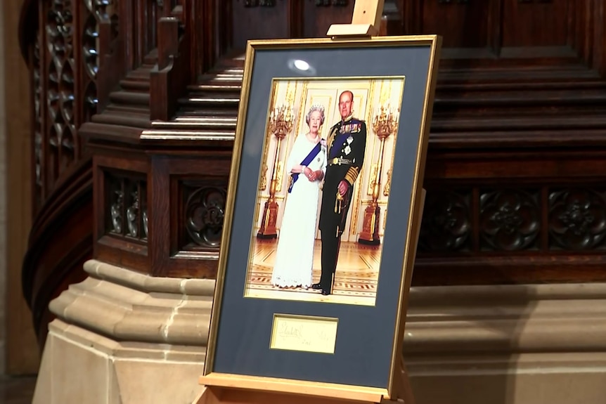A photograph of the Queen and Prince Philip sits below a pulpit.