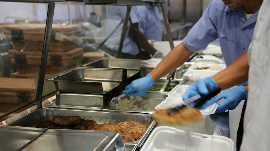 Unidentified workers prepare food in buffet trays