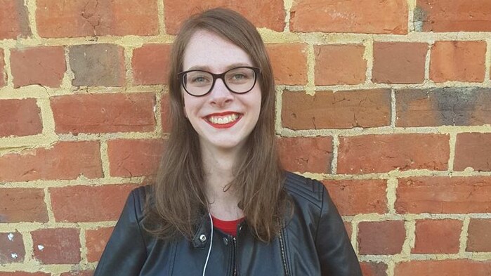 Madison Watts stands in front of a brick wall