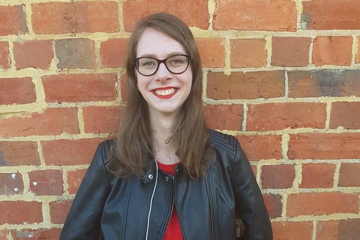 Madison Watts stands in front of a brick wall