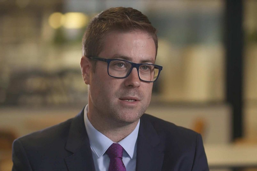 A man wears a suit and tie and glasses.