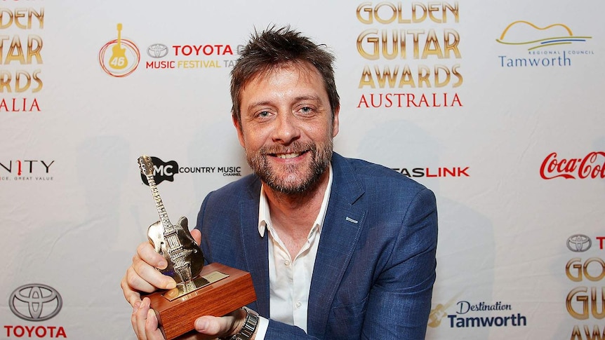 Shane Nicholson holding up his Golden Guitar award.