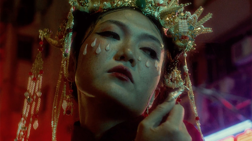 Rainbow Chan in an ornate headdress with tear-like makeup under her eyes.