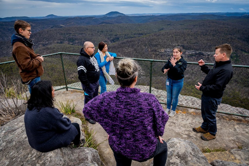 A woman AUSLAN signing in front of a group