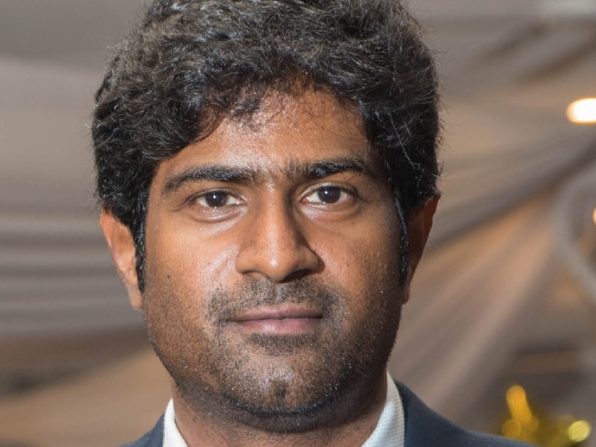 Kalyan Cherukuri looks at the camera while wearing a suit with a blue shirt and dark blue tie.