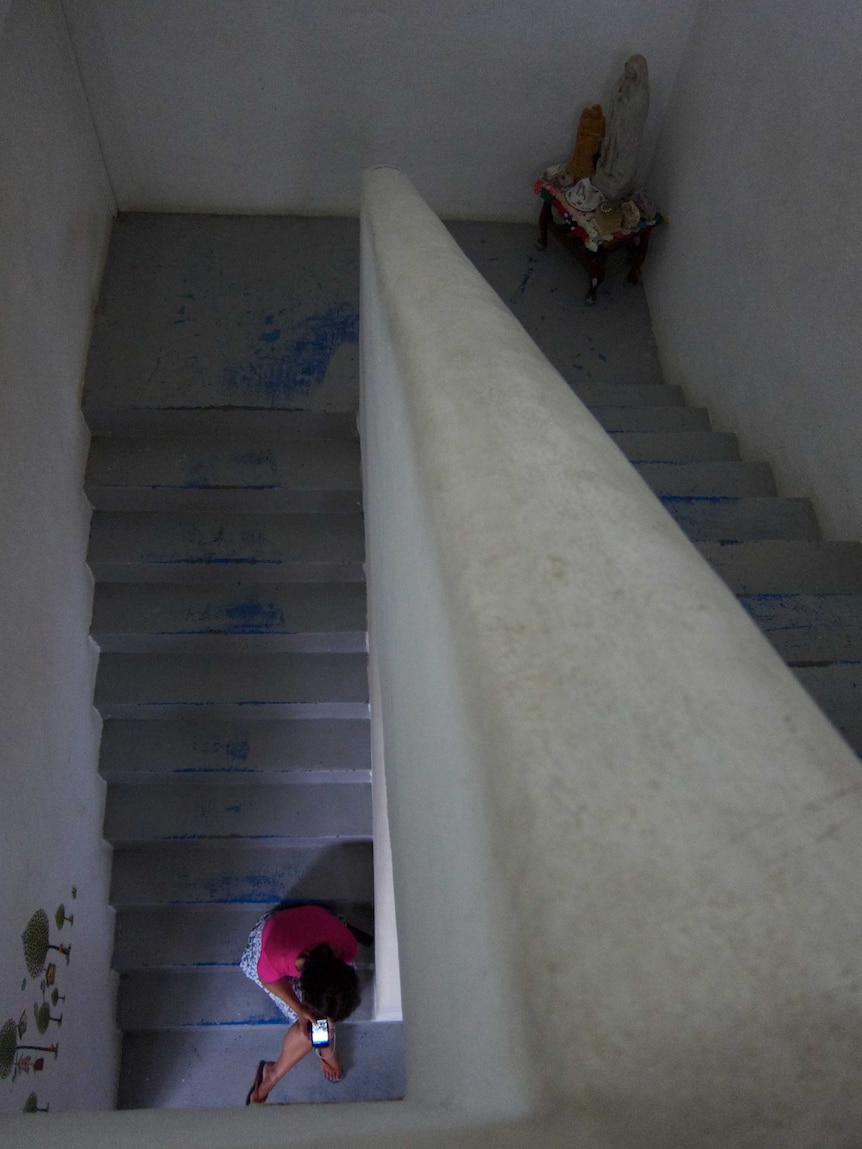 A migrant worker sits in a stairwell.
