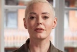 Rose McGowan looks down the camera, she has short bleached blonde hair.