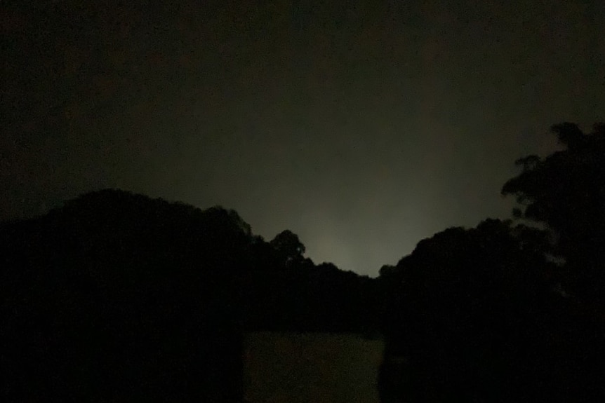 Light is seen on the horizon of a night time photo.
