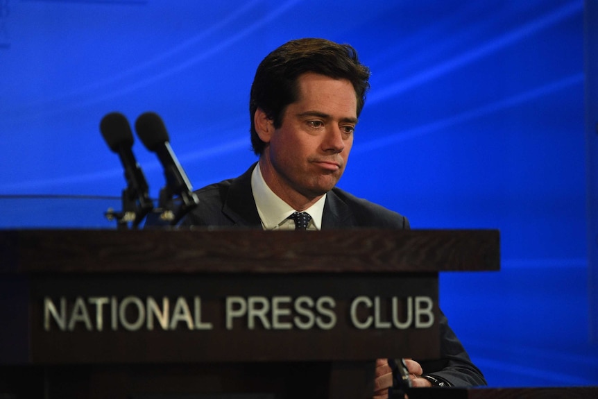 An AFL executive stands next to a lectern marked "National Press Club" after making a speech.