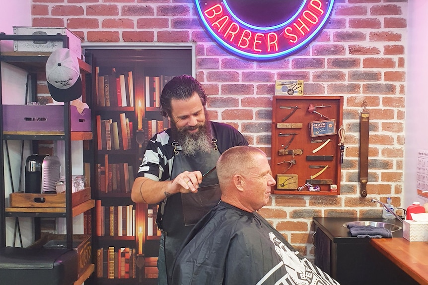 Barber Arren Heeley working with a client in his salon at Albany Creek, north of Brisbane.